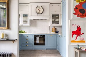 Una cocina con armarios blancos, encimera azul, un reloj y un cartel con un perro rojo.
