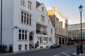 A white building with a balcony, a street lamp, and a car parked on the street. - William Mews by onefinestay (London)