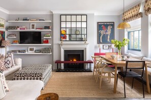 Un salon avec une cheminée, un coin repas et une bibliothèque.
