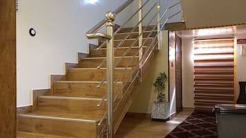 A staircase with wooden steps and a metal handrail, leading to a room with a patterned carpet and a door labeled "LOCAL TECHNIQUE."