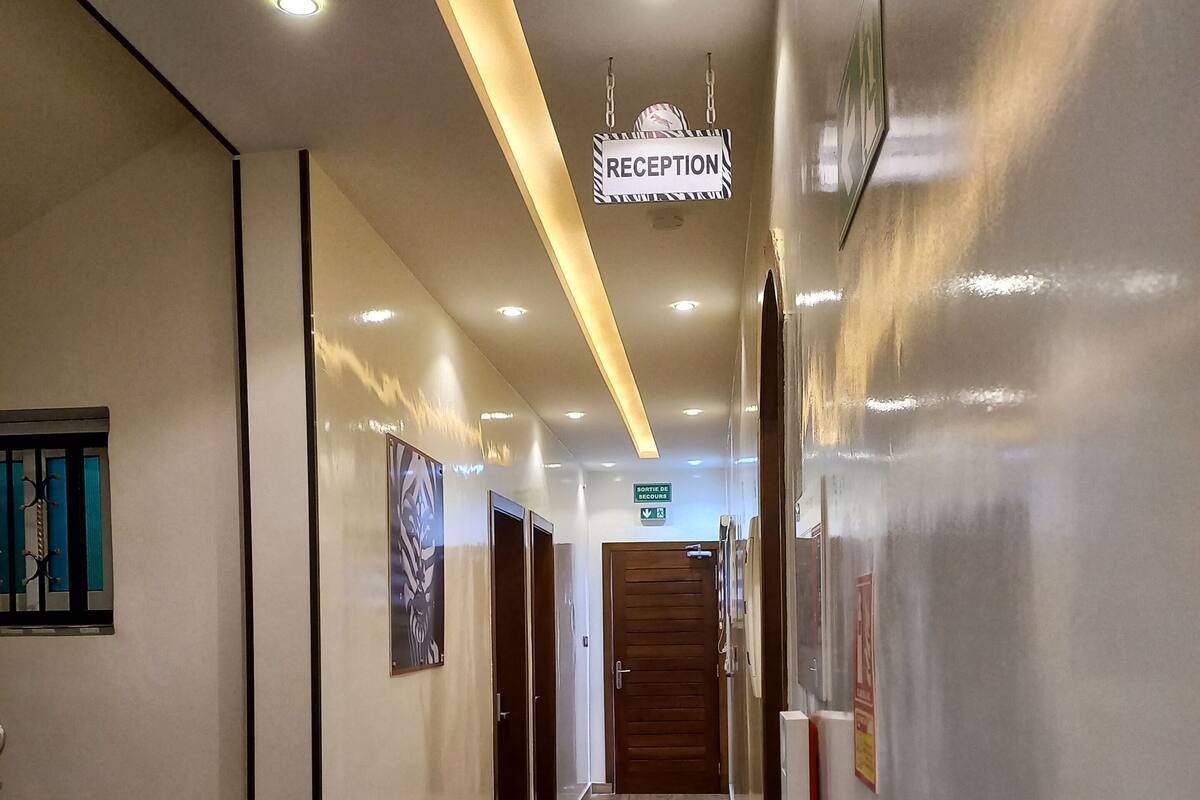 A hotel reception area with a reception desk, a fire extinguisher, and a sign indicating the reception.