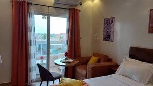 A hotel room with a bed, a chair, a small table, and a view of the outside. - ZEBRA RESIDENCE (Bambylor)