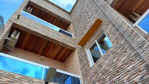A multi-story building with a modern architectural design, featuring exposed wooden beams and a textured facade. - ZEBRA RESIDENCE (Bambylor)