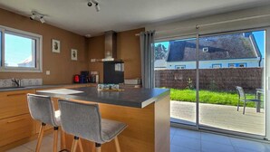 A modern kitchen with a large island, wooden cabinets, and a sliding glass door leading to a patio.