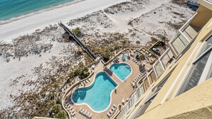 An aerial view of a resort with two swimming pools, a beach, and a building with balconies. - NEW 15th Floor Gulf View - Balcony - Pool - Hot Tub (Pensacola Beach)