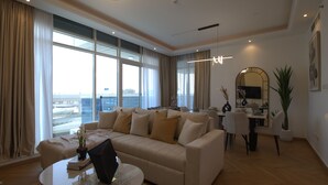 A modern living room with a beige sofa, a round coffee table, and a dining area with a white table and chairs.