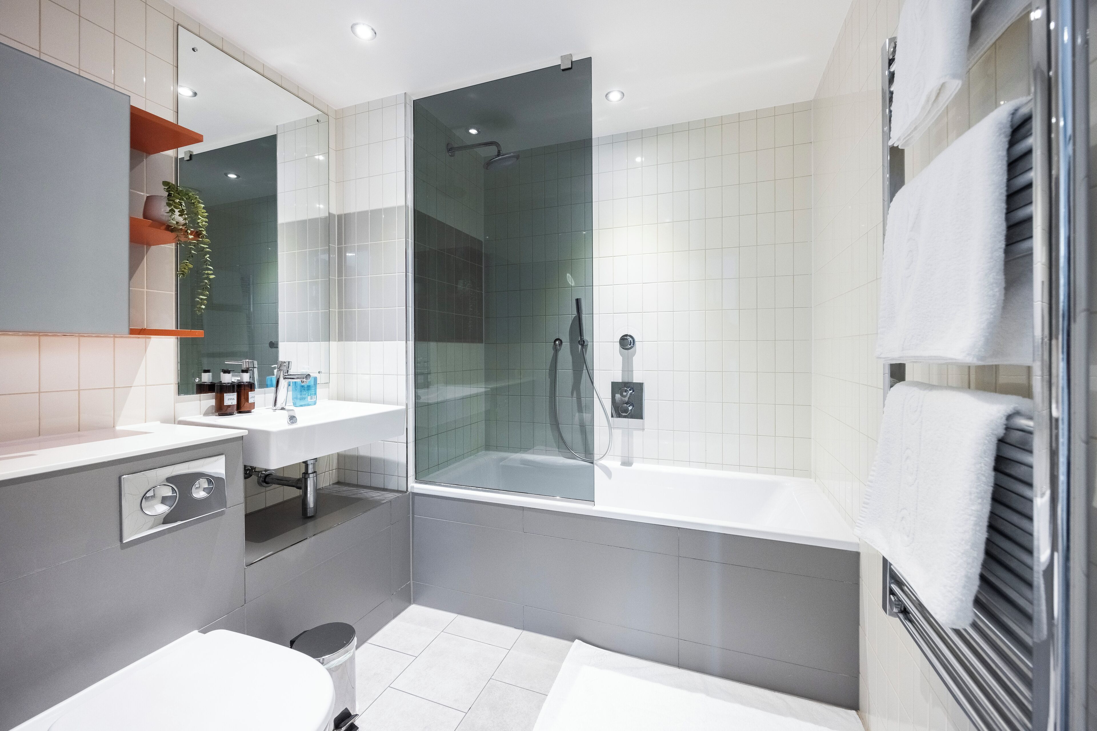 A modern bathroom with a glass-enclosed shower, a white sink, and a bathtub.