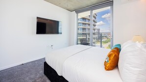 Ein modernes Hotelzimmer mit einem großen Bett, einem flachbildfernseher an der Wand und einem großen Fenster mit Blick auf die Stadt.
