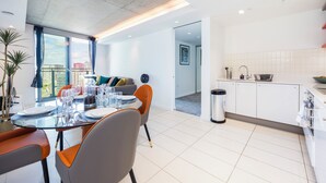 Ein modernes Wohnzimmer mit Essbereich, Küche und Blick auf die Stadt.