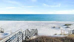 A beach with a wooden walkway leading to the water, sandy beach, and a clear blue sky. - Casita Bonita at Eleanor Beach (Pensacola)