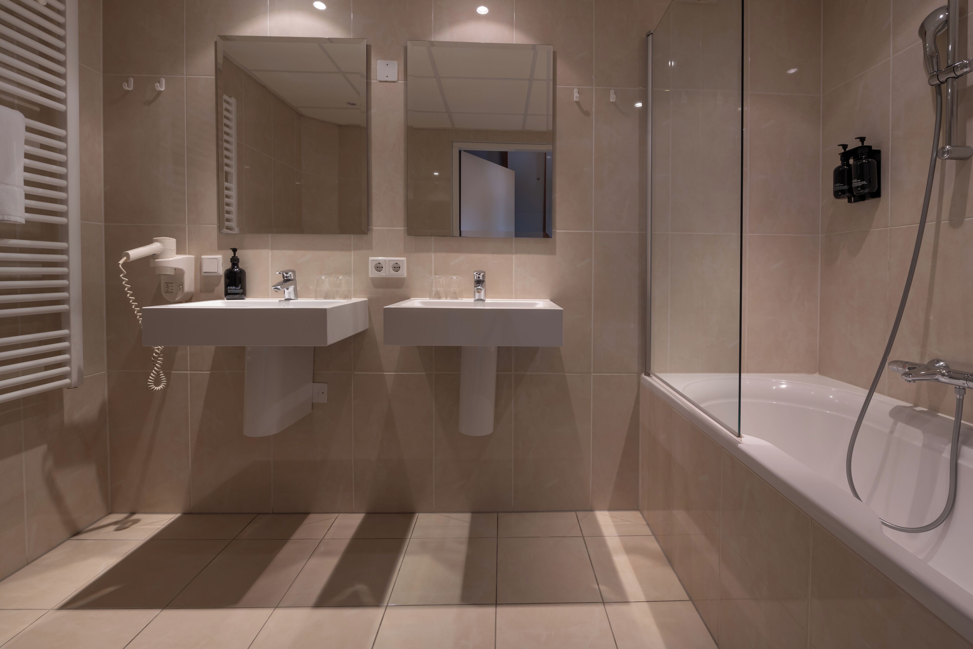 Un baño moderno con dos lavamanos, un espejo grande y una ducha a ras de suelo.