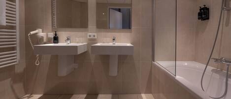 Ein modernes Badezimmer mit zwei Waschbecken, einem großen Spiegel und einer begehbaren Dusche.