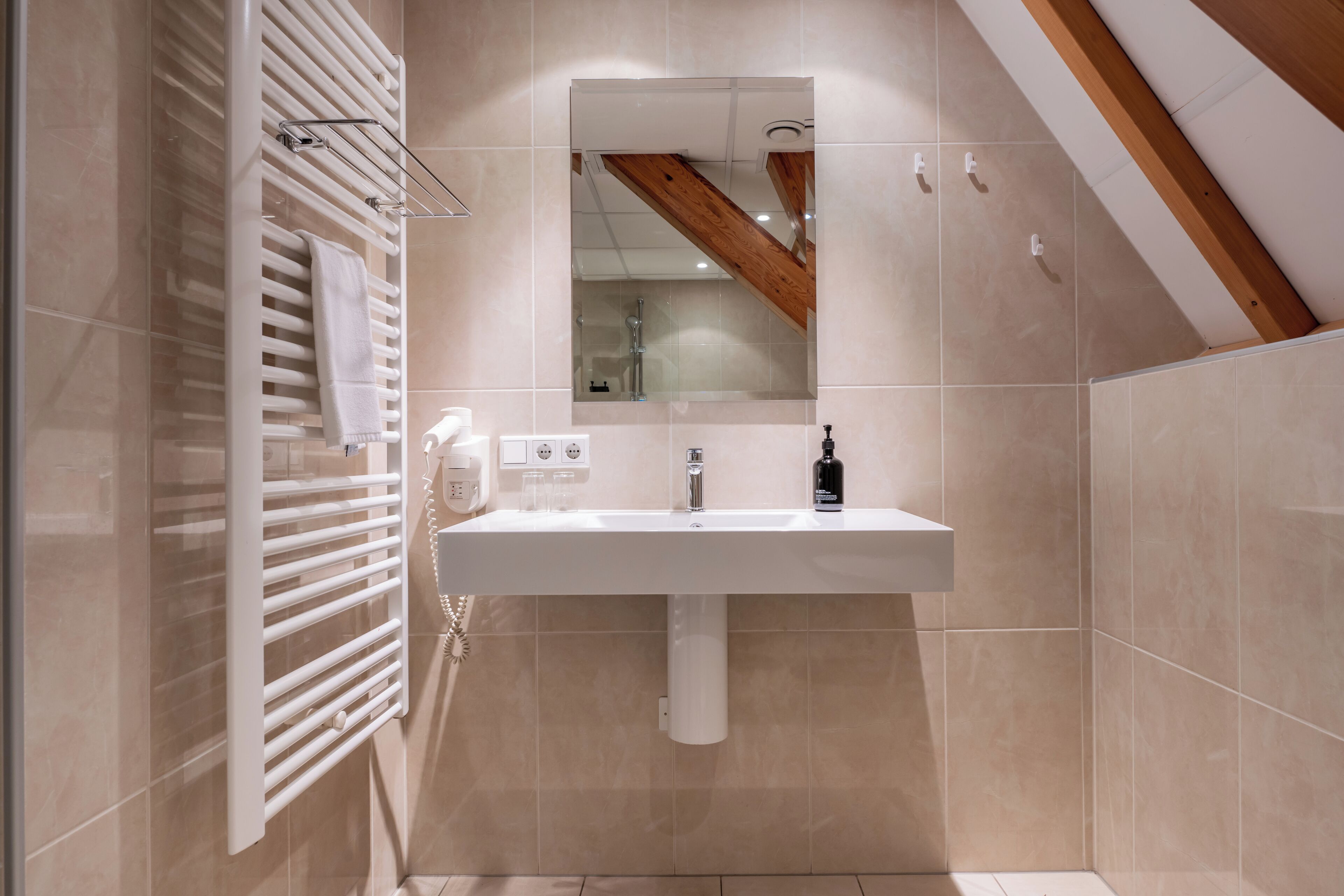 A modern bathroom with a white sink, a mirror, and a towel rack.