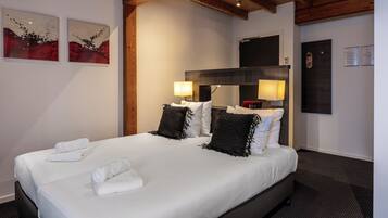 Ett hotellrum med en stor säng, två sänglampor och konstverk på väggen.