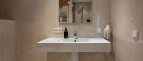 A modern bathroom with a white sink, a mirror above it, and a shower visible in the background.