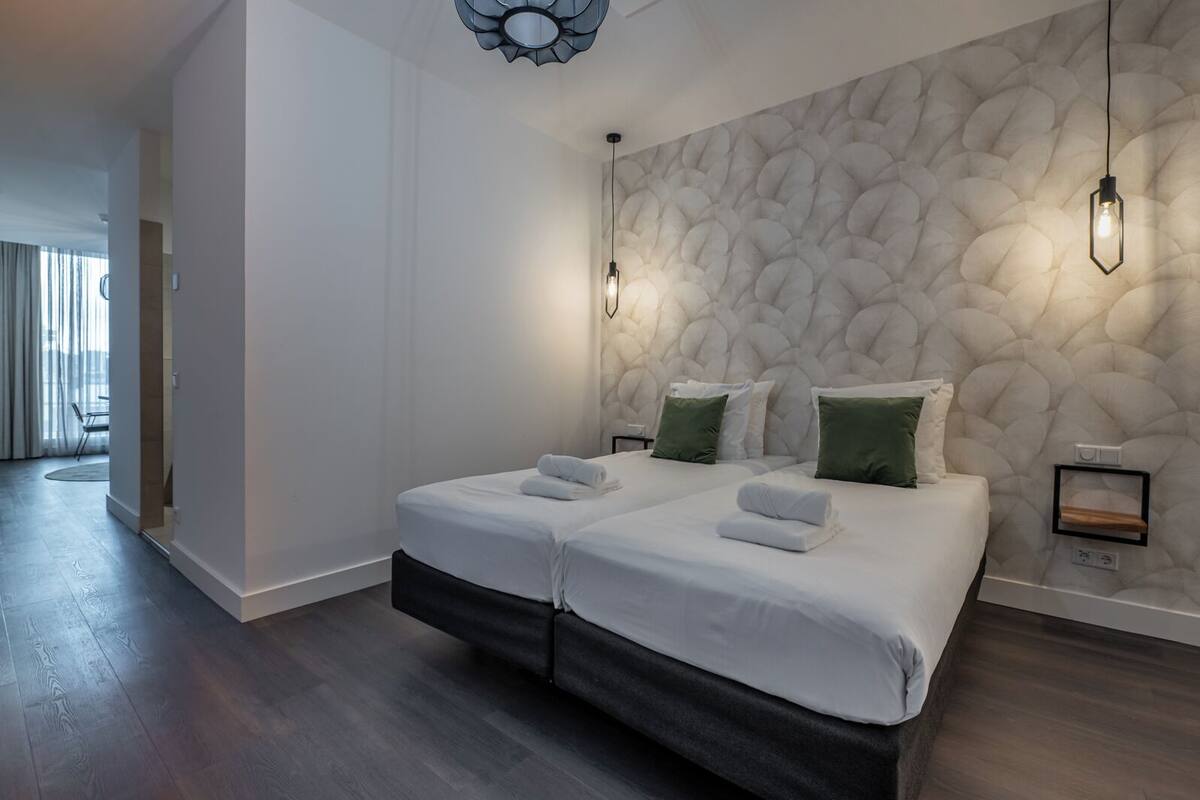 Una habitación de hotel moderna con una cama grande, dos mesitas de noche y un llamativo muro con textura.