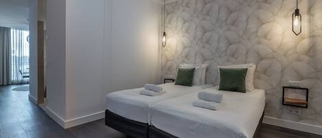 Una habitación de hotel moderna con una cama grande, dos mesitas de noche y un llamativo muro con textura.