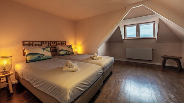 Ein Schlafzimmer mit zwei Betten, Holzboden, Heizkörper und einem kleinen Tisch.