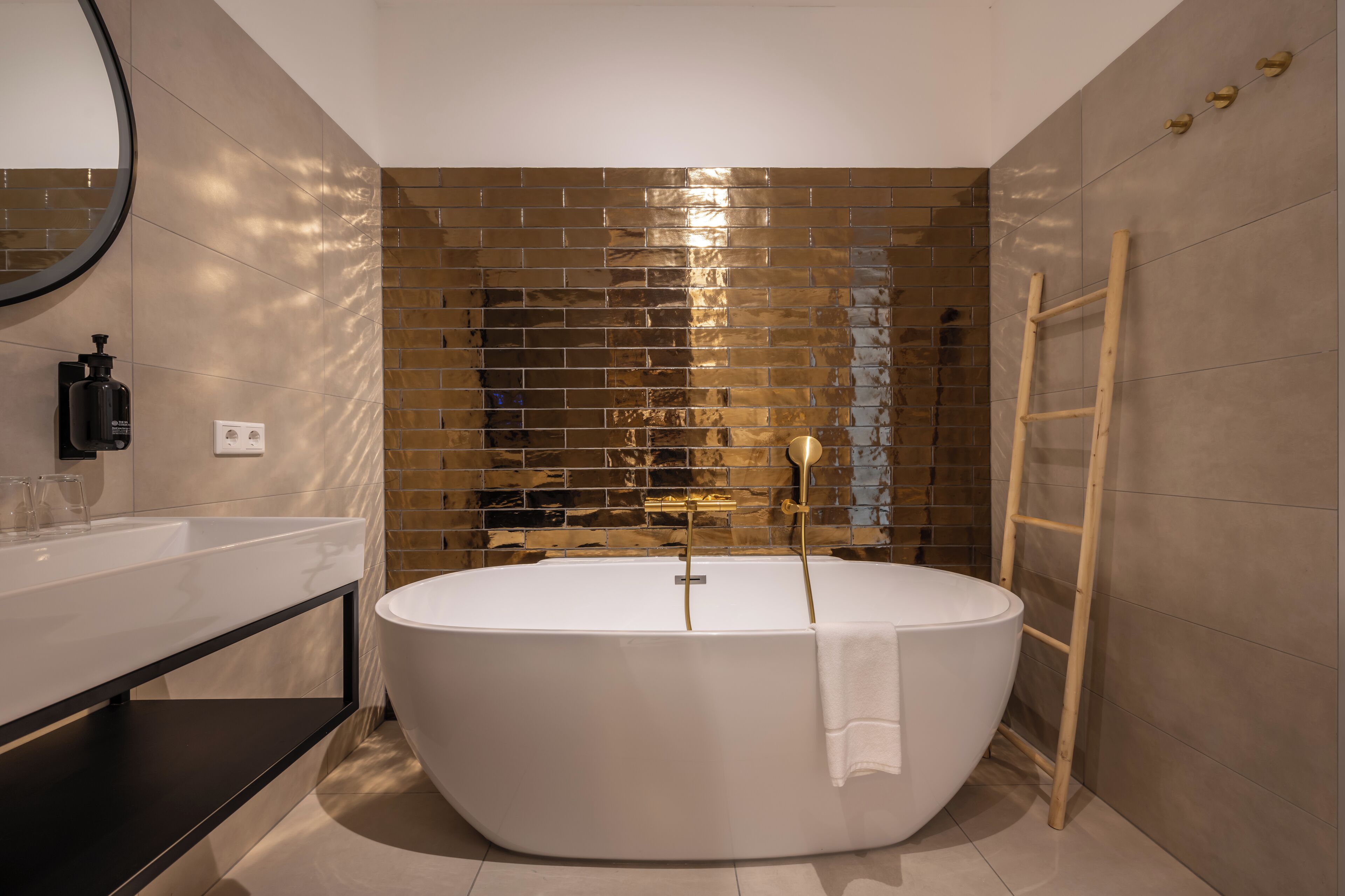 Un baño moderno con una bañera independiente, una escalera de madera y un espejo.
