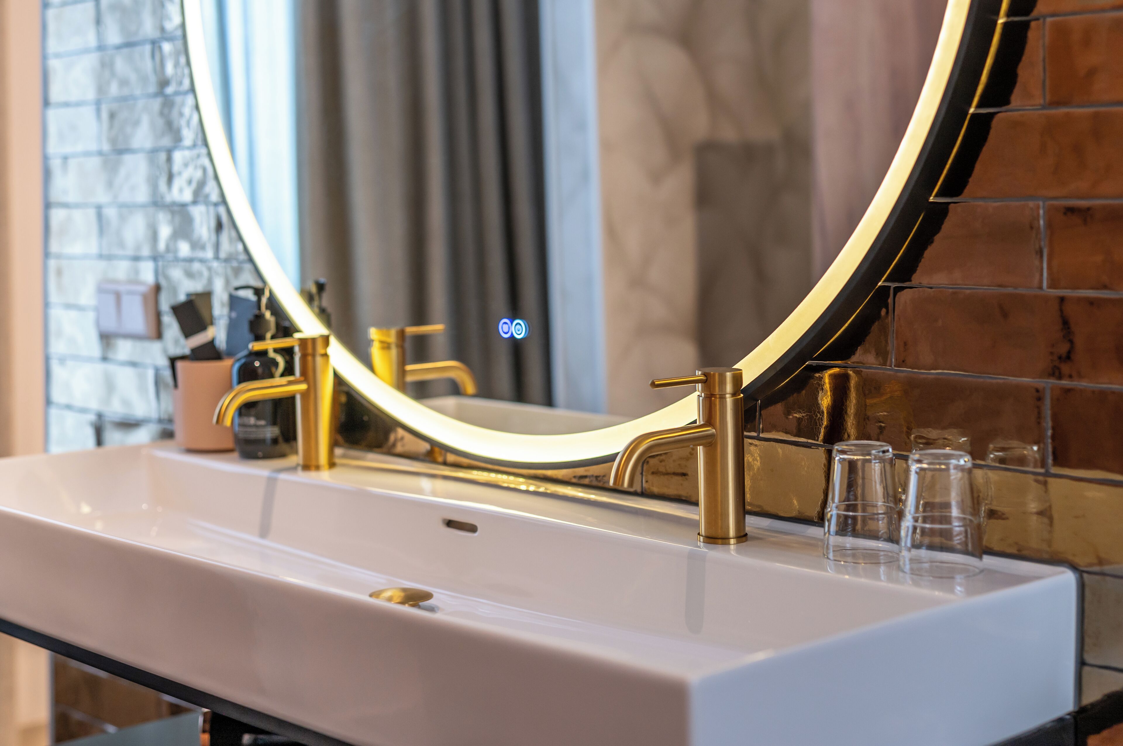 Een badkamer met een witte wastafel, gouden kraanwerk en een grote spiegel met gouden lijst.