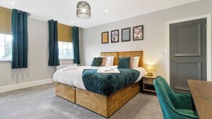A bedroom with a bed, bedside table, lamp, and a door. - WhiskAwayStays  Victoria House  Apartment 4 (Worcester)