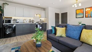 A modern apartment with a kitchen, living area, and a sofa with cushions. - WhiskAwayStays  Victoria House  Apartment 4 (Worcester)