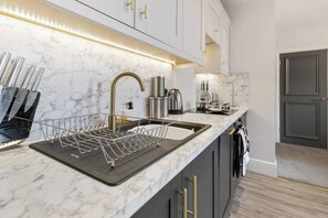 A modern kitchen with a marble countertop, stainless steel appliances, and gold handles on the cabinets. - WhiskAwayStays  Victoria House  Apartment 4 (Worcester)