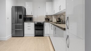 Eine moderne Küche mit Edelstahlgeräten, weißen Schränken und Holzboden.