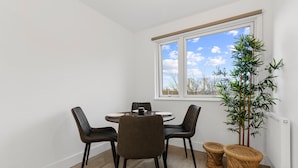 Ein Essbereich mit einem runden Tisch, vier Stühlen, einer Topfpflanze und zwei Weidekorbstühlen.