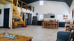 A spacious living area with a wooden staircase, a dining table with chairs, a kitchen with modern appliances, and a cozy seating area with a couch.