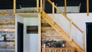 A wooden staircase with a metal railing leading to a loft area.