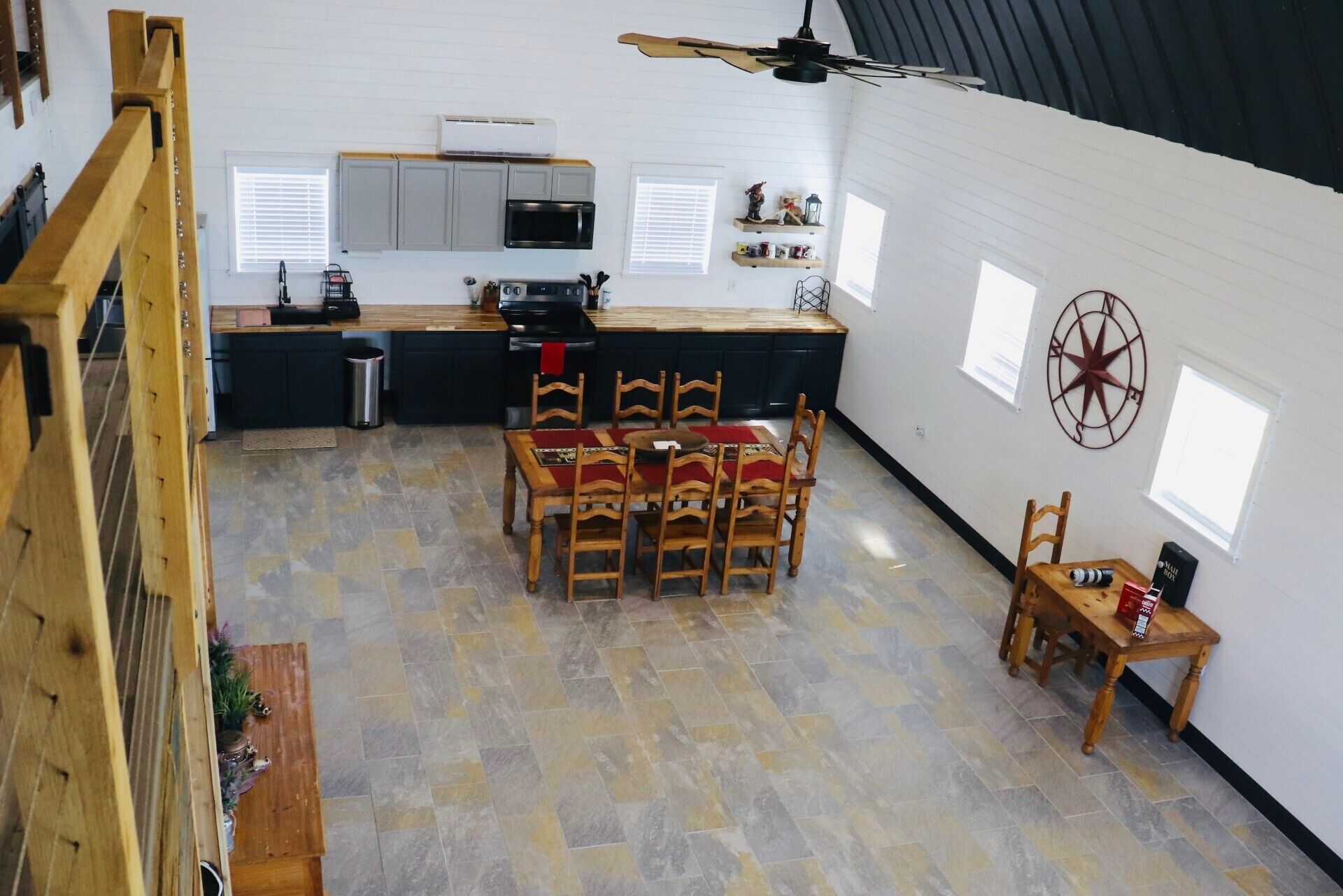 A spacious kitchen with a dining area, a ceiling fan, and a decorative compass on the wall.