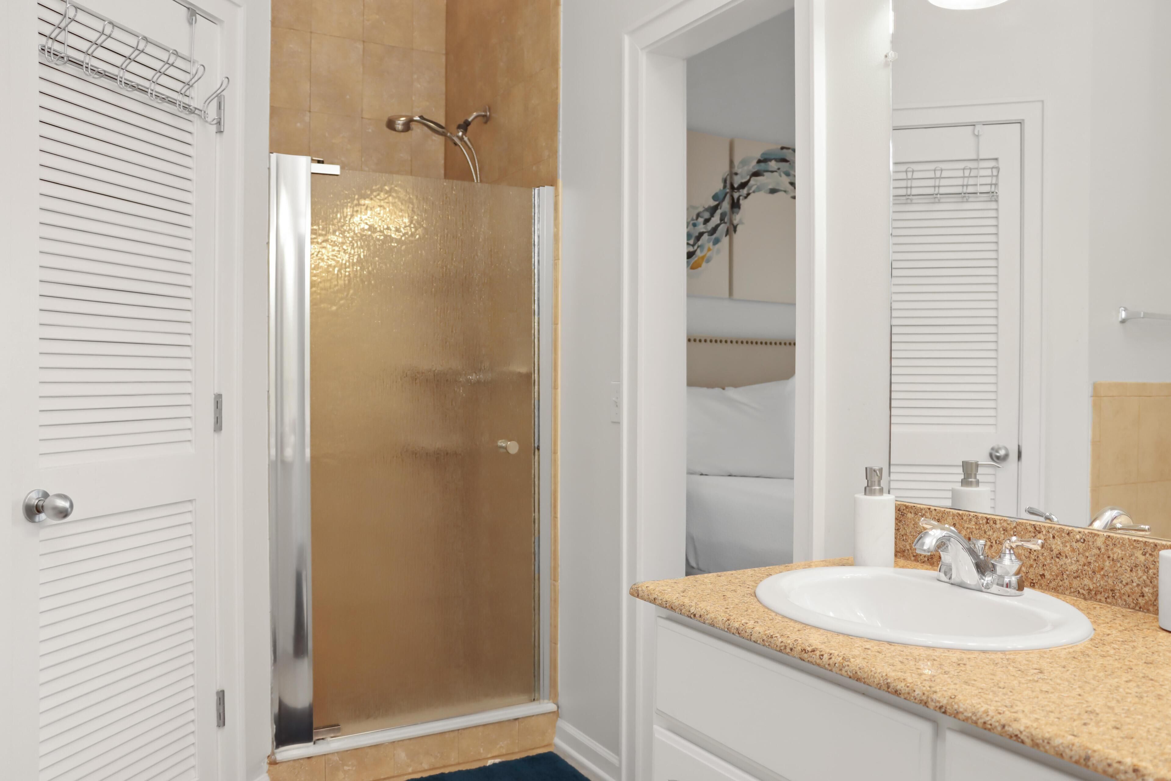 A bathroom with a shower, sink, and mirror.