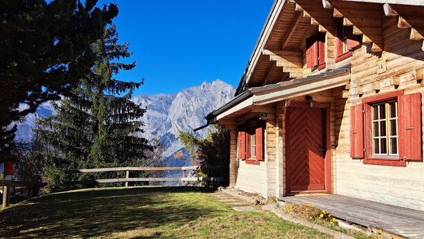 A wooden cabin with a wooden deck, a large wooden barrel, and a mountain backdrop. - Authentic chalet for 6 pers - A charming place 5 min from Nendaz station  (Nendaz)