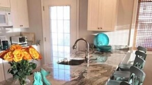 A kitchen with a marble countertop, a sink, and a vase of flowers. - Spacious 4-bedroom condo steps from The Starboard in Dewey Beach (Dewey Beach)