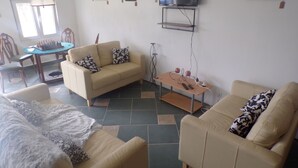 A living room with a sofa, a coffee table, and a TV mounted on the wall. There are framed pictures on the wall and a chessboard on the table. - Apartment Sleeps 4 With Private Pool (Jumilla)