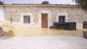 A stone building with a wooden door, two windows, and a patio area with outdoor furniture. - Apartment Sleeps 4 With Private Pool (Jumilla)