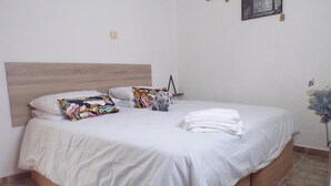 A neatly made bed with white linens, a wooden headboard, and colorful pillows. - Apartment Sleeps 4 With Private Pool (Jumilla)