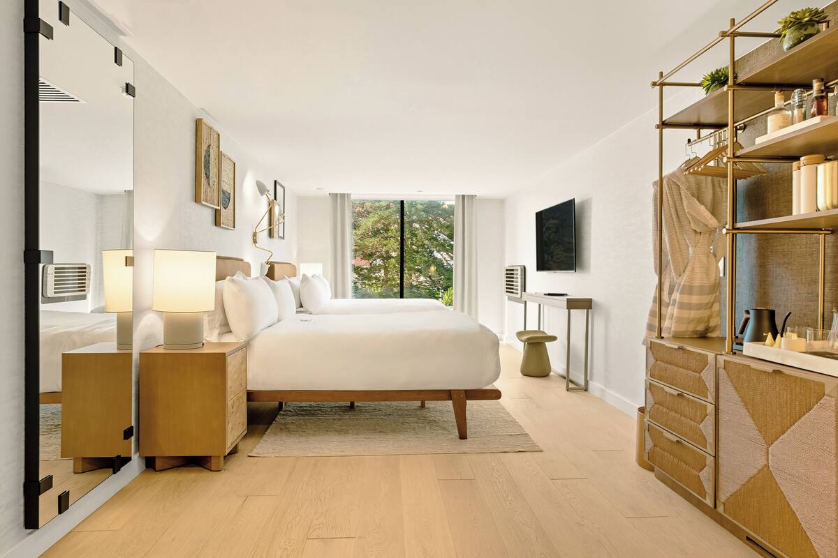 A modern bedroom with a large bed, bedside tables, a TV, and a wardrobe.