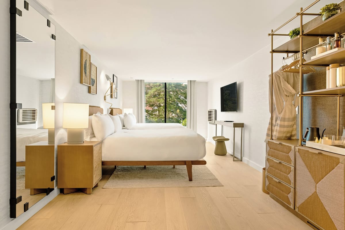 A modern bedroom with a large bed, bedside tables, a TV, and a wardrobe.
