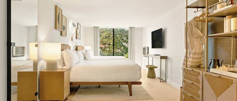 Een moderne slaapkamer met een groot bed, nachtkastjes, een televisie en een kledingkast.
