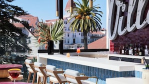 An outdoor bar area with a pool, bar stools, and a large 'VILL' sign. - The Bower Coronado (Coronado)