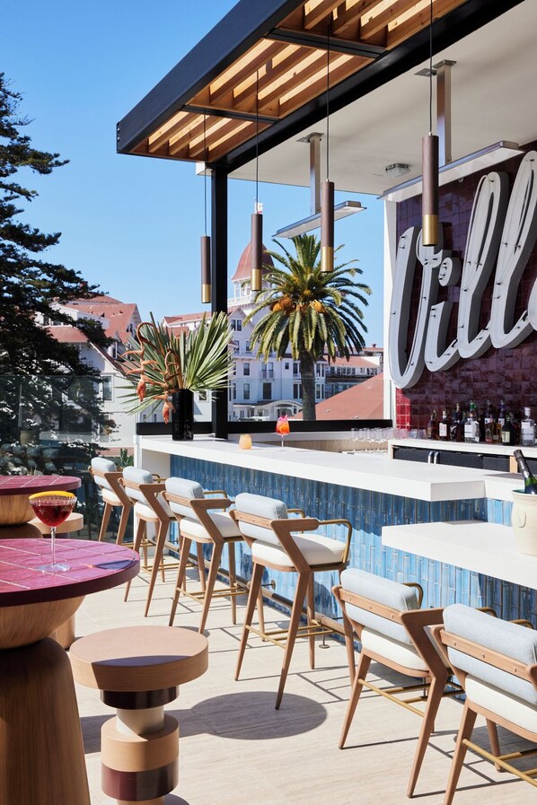 An outdoor bar area with a pool, bar stools, and a large 'VILL' sign. - The Bower Coronado (Coronado)