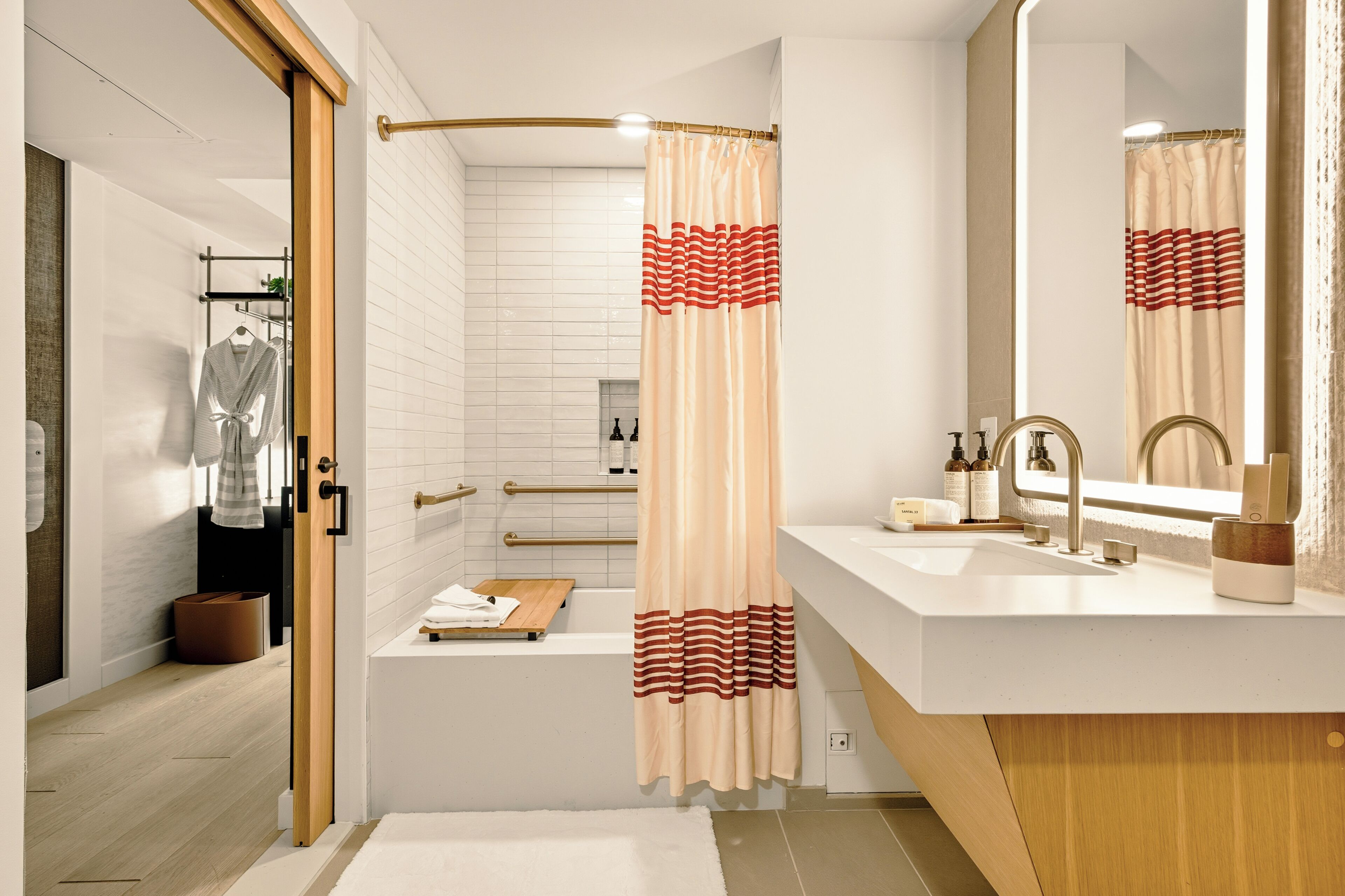 Un baño moderno con ducha, tocador con espejo y toallero.