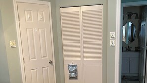 Ein Schlafzimmer mit Bett, Schrank und einem durch eine offene Tür erreichbaren Badezimmer.