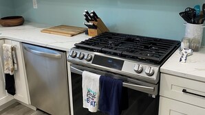 Eine moderne Küche mit Edelstahlgeräten, darunter eine Mikrowelle, ein Herd und eine Spülmaschine.