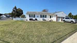 Ein eingeschossiges Haus mit Veranda, Garage und gepflegtem Rasen.