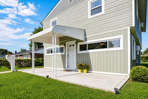 A two-story house with a covered porch, a front door, and a small garden with potted plants. - Spacious 5-bedrooms in Catonsville, MD near BWI, UMBC, Baltimore, Patapsco Park (Catonsville)