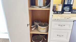 A kitchen with white cabinetry, a coffee machine, and various pots and pans on shelves.