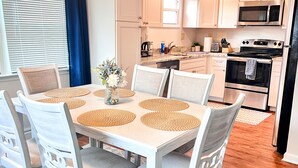 A modern kitchen with white cabinets, a stainless steel microwave, an oven, and a dishwasher.
